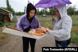 Девушка угощает поминальным пирогом на крымскотатарском кладбище. Село Х. Бижанова, Алматинская область. 5 мая 2022 года.