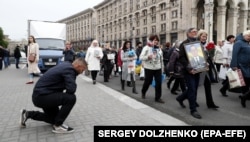 Мужчина преклонил колено перед шествием, посвященном памяти всех жертв российско-украинского конфликта. Киев, 8 мая 2019 года