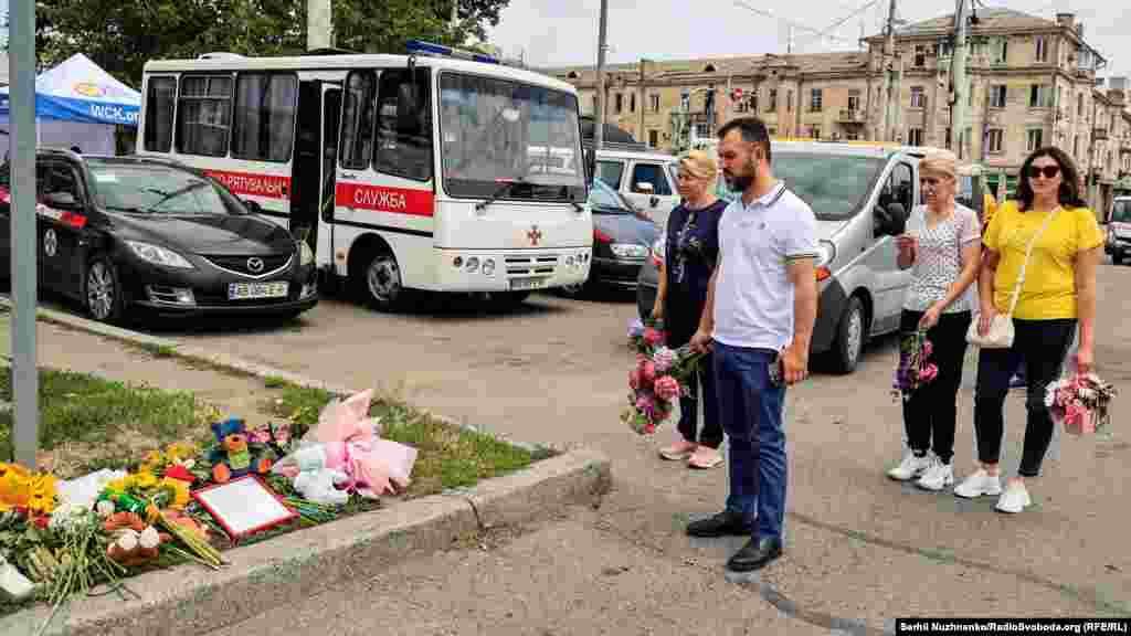 Люди возлагают цветы у импровизированного мемориала. На этом месте погибла четырехлетняя Лиза Дмитриева