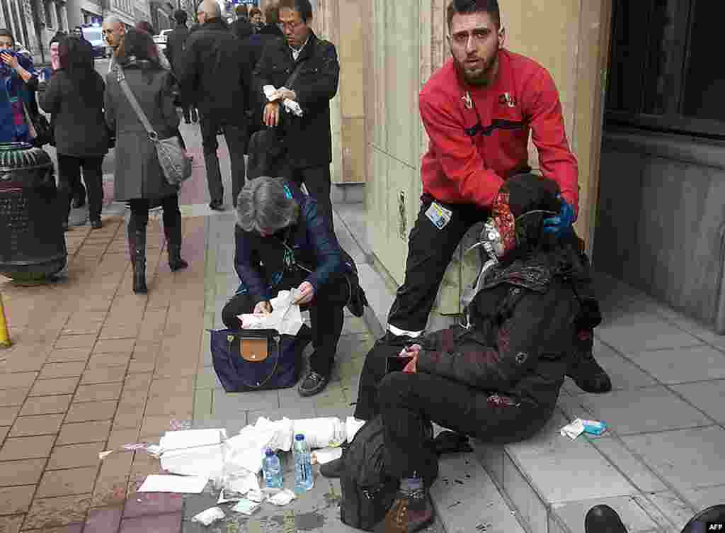 Maalbeek metro partlayışı. Özəl şirkətin təhlükəsizlik əməkdaşı yaralanan şəxsə kömək edir.