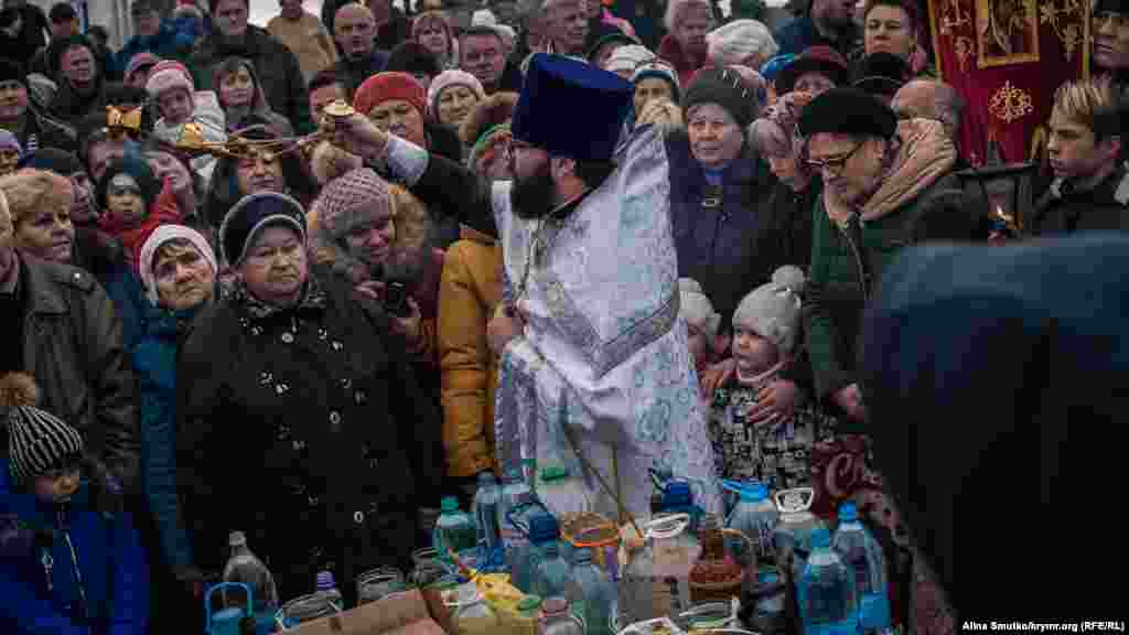 Горожане с детьми во время молитвы возле причала